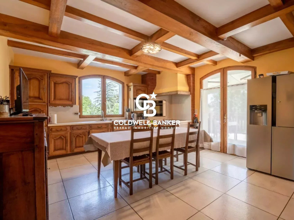 Cuisine spacieuse et lumineuse avec table à manger et fenêtres donnant sur l'extérieur.