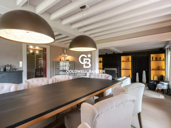 Intérieur d'une ferme rénovée avec une grande table à manger et des luminaires modernes.
