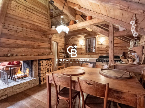Intérieur d'une ferme rénovée avec un coin repas en bois et une cheminée.
