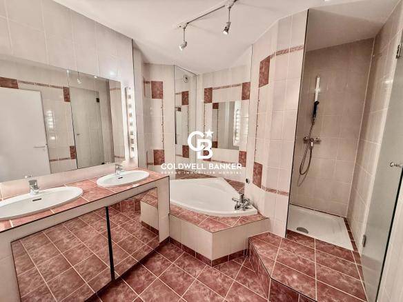 Spacious bathroom with bath and shower, ceramic tiles, mirror and modern lighting.