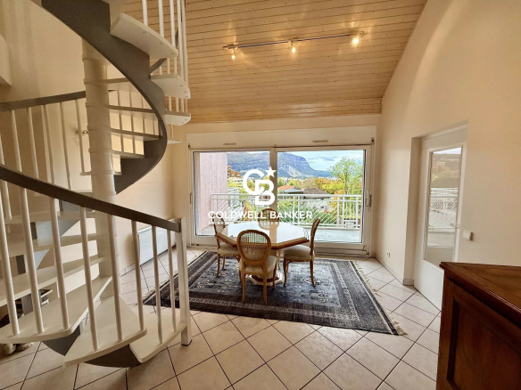 Interior of a duplex apartment in Ambilly with a spiral staircase and a view of the mountains.