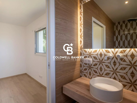 Modern bathroom with decorative tiles and a washbasin on a wooden vanity.