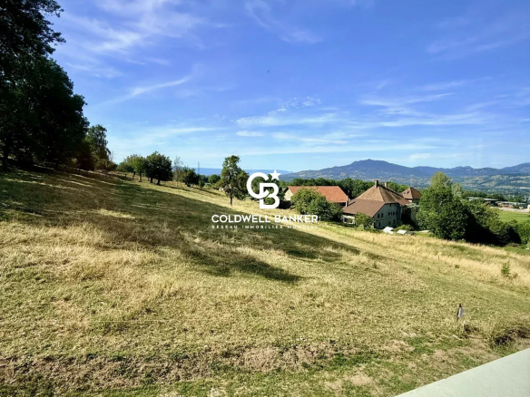 Unobstructed view of a green landscape with houses and mountains in the background in Etaux.