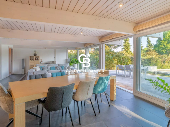 Intérieur d'une maison moderne avec baies vitrées et salle à manger lumineuse.