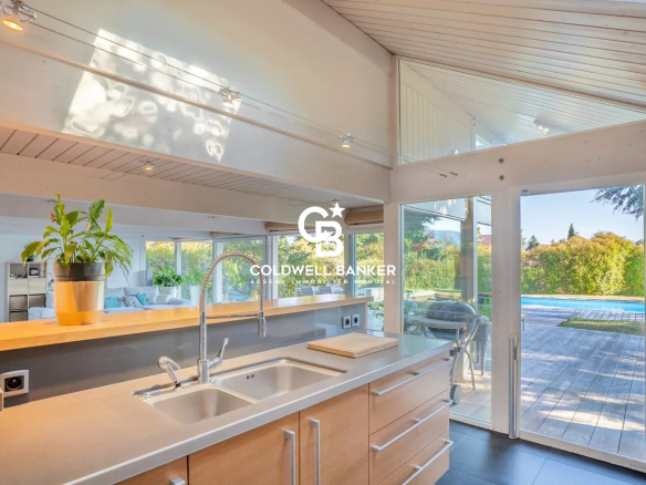 Cuisine moderne avec vue sur le jardin et la piscine dans une maison à Vétraz-Monthoux.