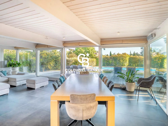 Intérieur d'une maison familiale avec salle à manger et baies vitrées donnant sur le jardin et la piscine.