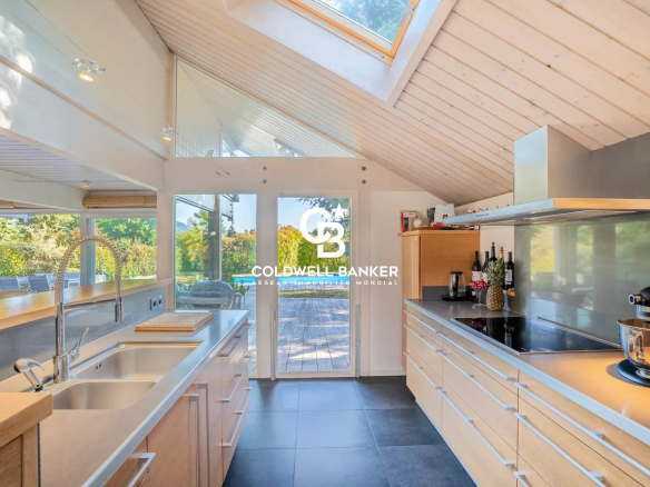 Cuisine moderne avec baies vitrées donnant sur le jardin dans une maison à Vétraz-Monthoux.