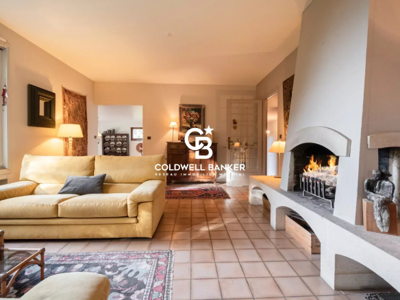 Intérieur d'une villa avec salon lumineux, cheminée et canapé, à Vétraz-Monthoux.