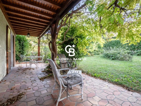 Terrasse d'une villa à Vétraz-Monthoux avec des chaises et un jardin verdoyant.