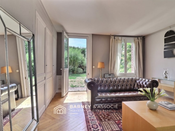 Intérieur d'une maison ancienne avec un salon et vue sur le jardin.