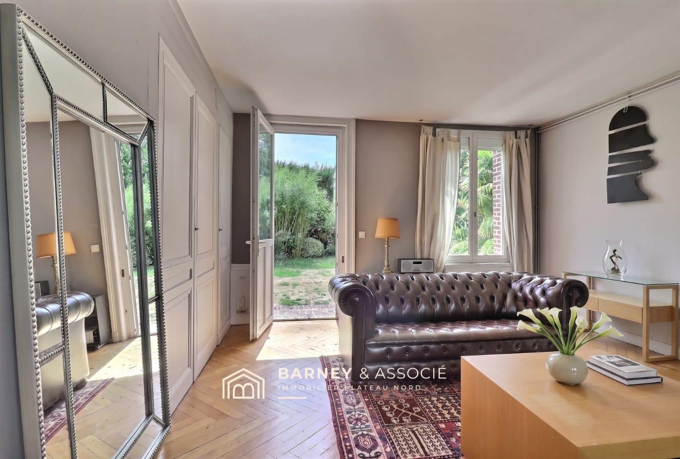 Intérieur d'une maison ancienne avec un salon et vue sur le jardin.