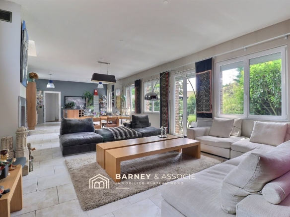 Intérieur d'une maison rénovée avec un grand salon lumineux et vue sur le jardin.