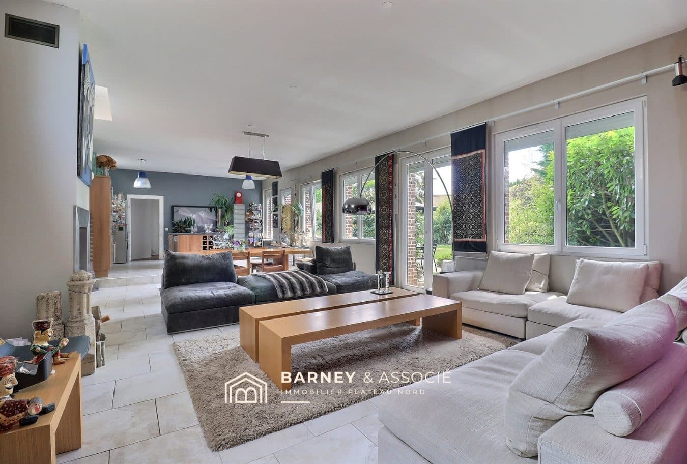 Intérieur d'une maison rénovée avec un grand salon lumineux et vue sur le jardin.