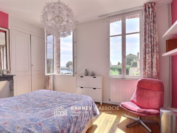 Chambre avec lit et fenêtre donnant sur le jardin, murs roses et décoration moderne.
