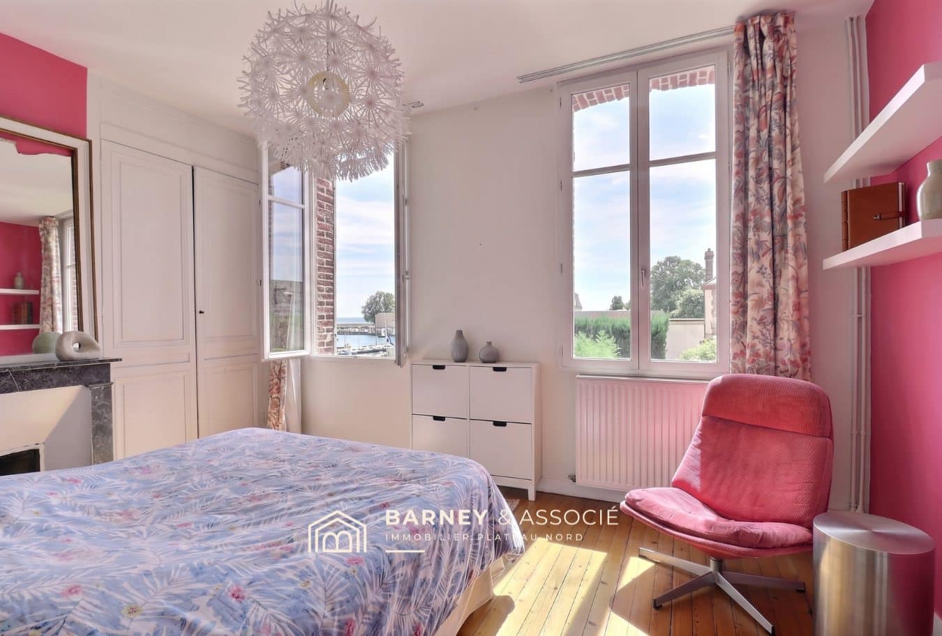 Chambre avec lit et fenêtre donnant sur le jardin, murs roses et décoration moderne.