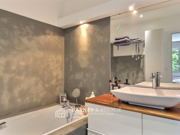 Salle de bain moderne avec baignoire et lavabo sur un plan en bois.