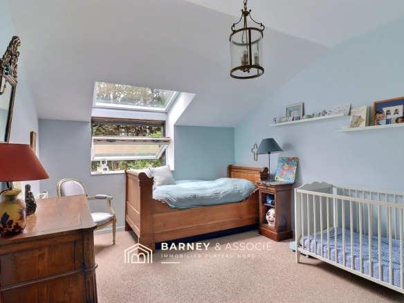 Chambre d'une maison familiale avec lit, berceau et mobilier en bois.