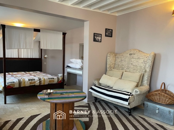 Intérieur d'une maison de campagne avec lit à baldaquin et coin salon.
