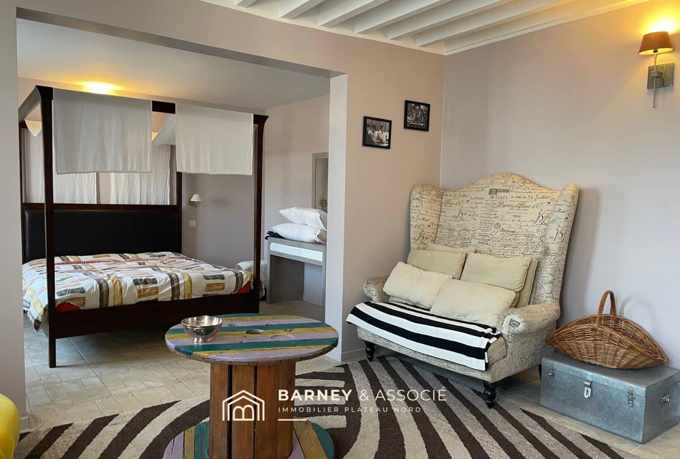 Intérieur d'une maison de campagne avec lit à baldaquin et coin salon.