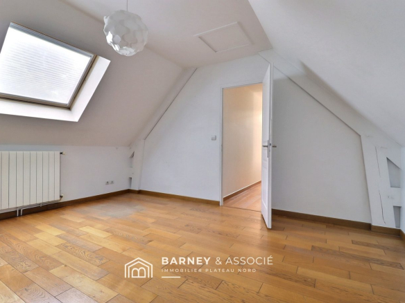 Intérieur d'une maison d'architecte avec un plafond mansardé et un parquet en bois.