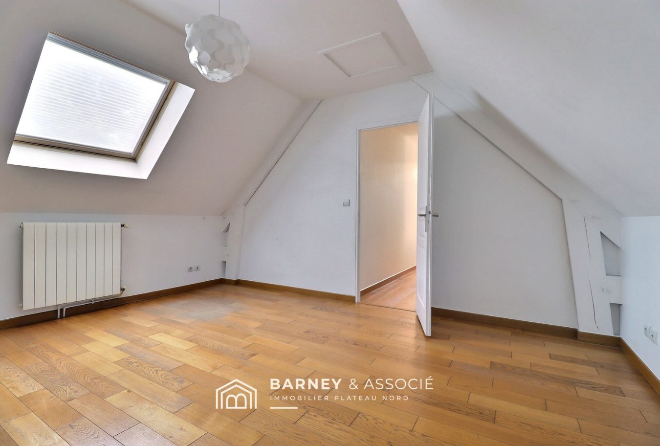 Intérieur d’une maison d’architecte Intérieur d'une maison d'architecte avec un plafond mansardé et un parquet en bois.