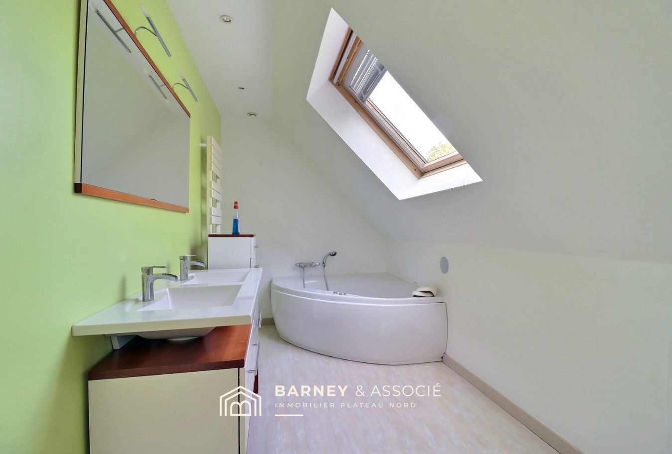 Salle de bain d’une maison d’architecte Salle de bain moderne avec baignoire et double vasque sous un plafond incliné.