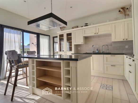 Modern and bright kitchen with bar, light wood furniture and windows overlooking the outside.