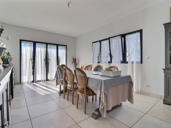 Bright dining room with large windows and a table for eight people in a contemporary house.