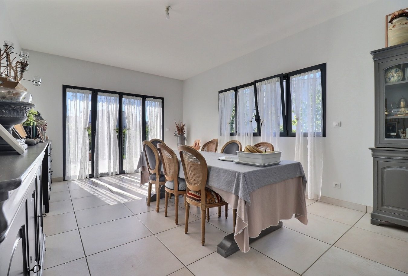 Salle à manger d’une maison contemporaine Salle à manger lumineuse avec grandes fenêtres et table pour huit personnes dans une maison contemporaine.