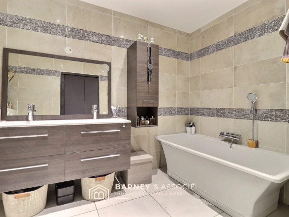 Modern bathroom with bathtub and double sink.