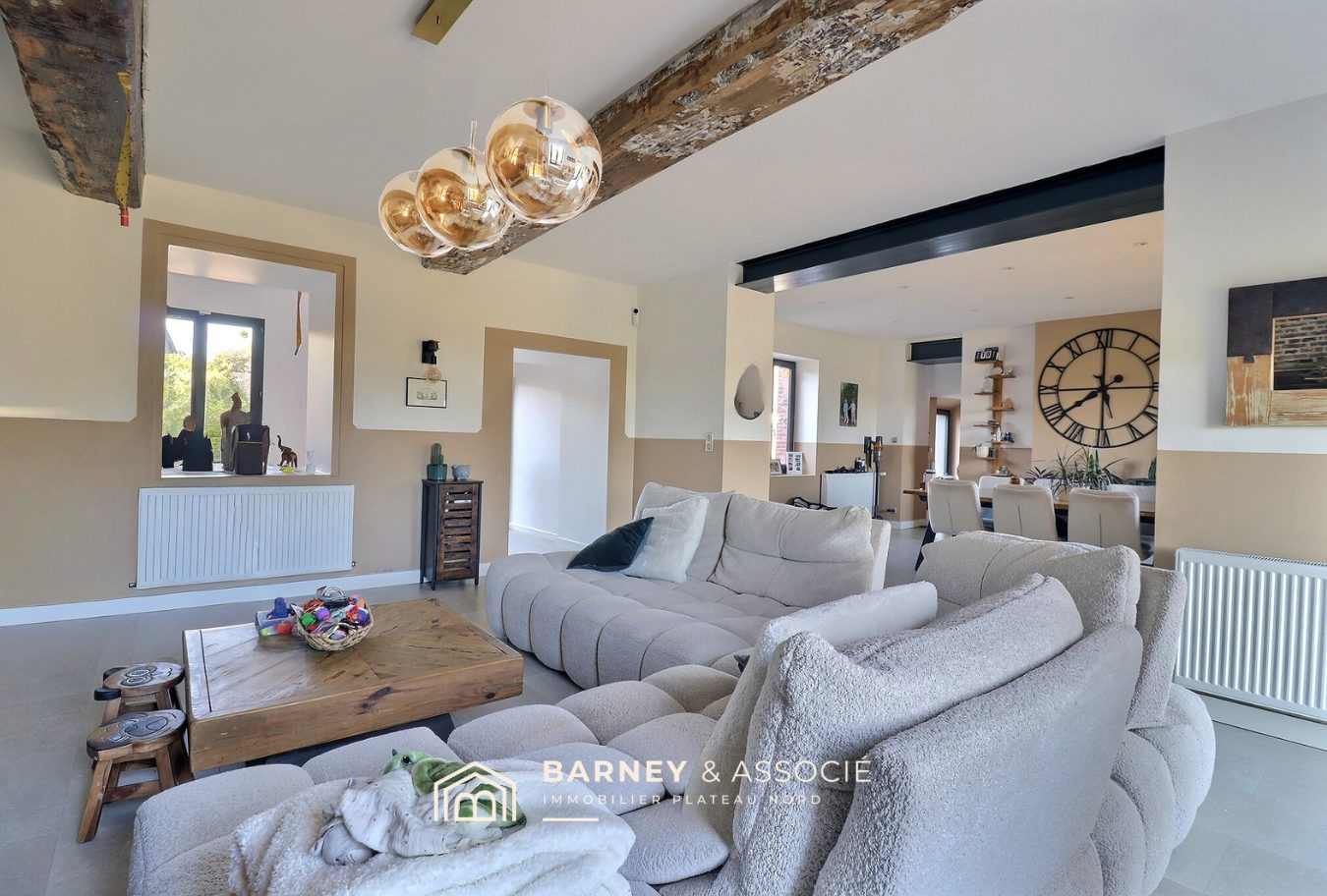 Intérieur d'une maison rénovée avec salon et salle à manger, décoration moderne et lumineuse.