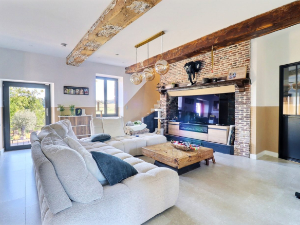 Intérieur d'une maison rénovée avec un salon spacieux et une cheminée en briques.