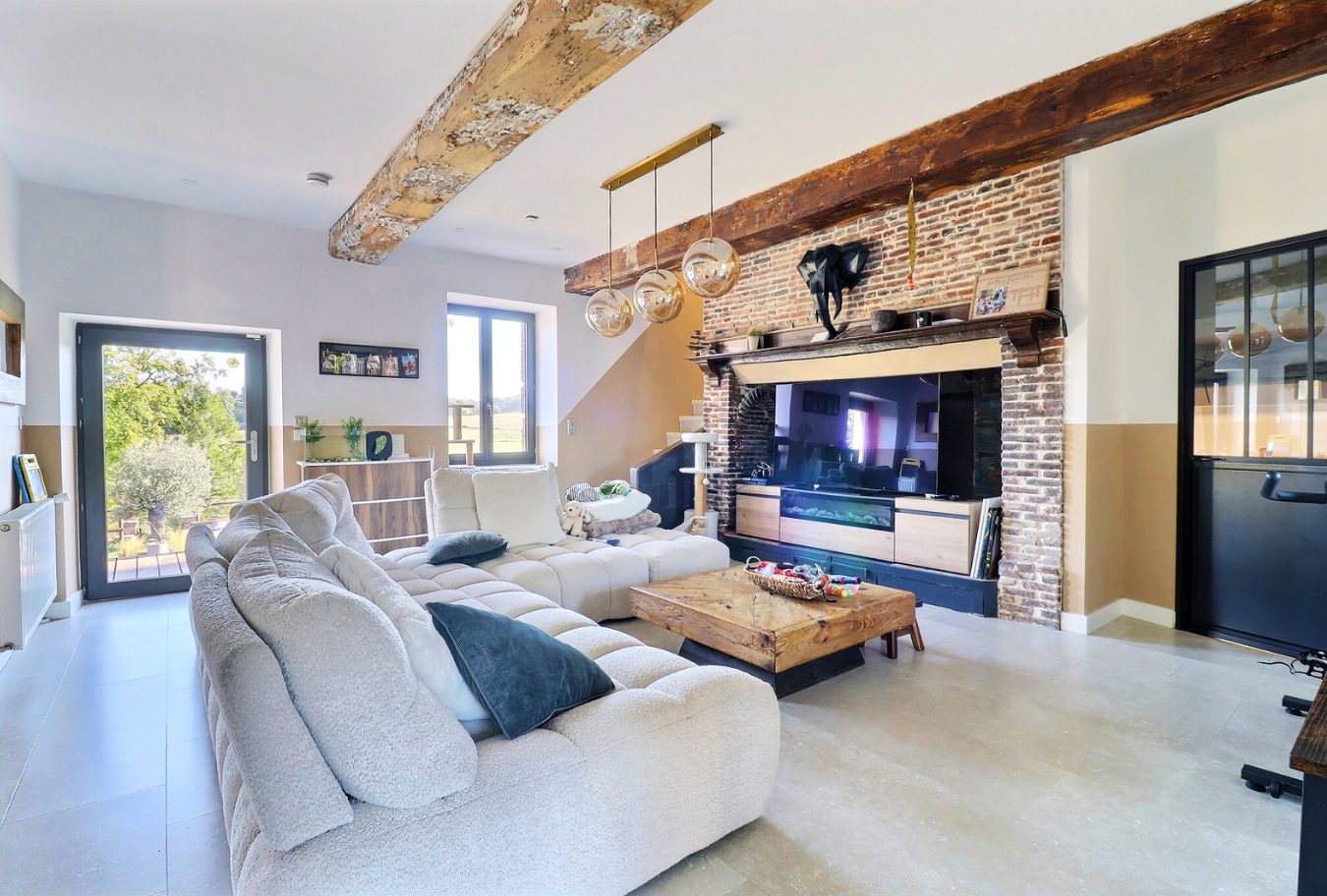 Intérieur d'une maison rénovée avec un salon spacieux et une cheminée en briques.