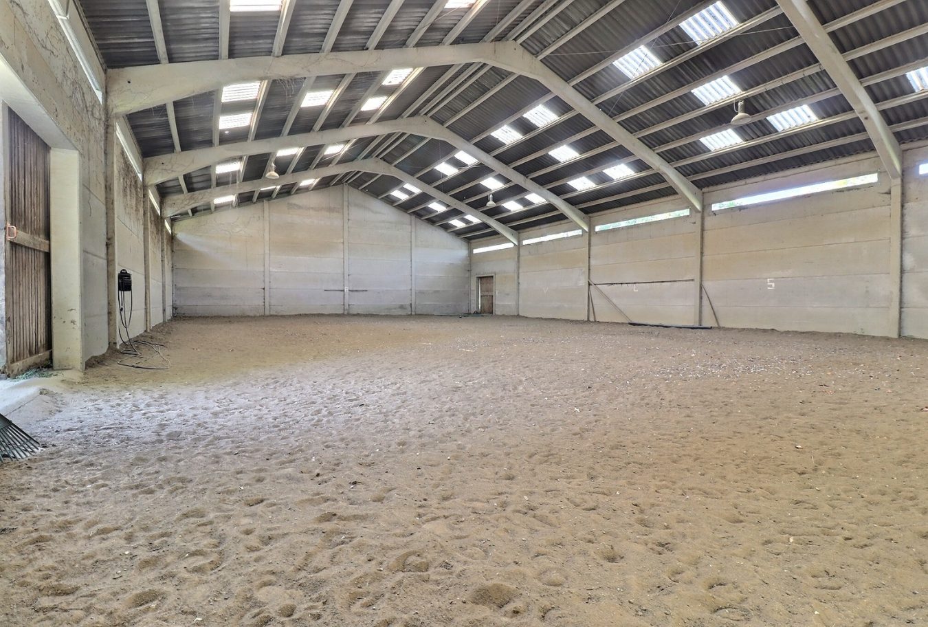 Intérieur d'une carrière équestre spacieuse avec sol en sable