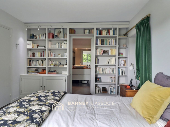 Chambre avec bibliothèque intégrée et lit, vue sur l'espace de vie.