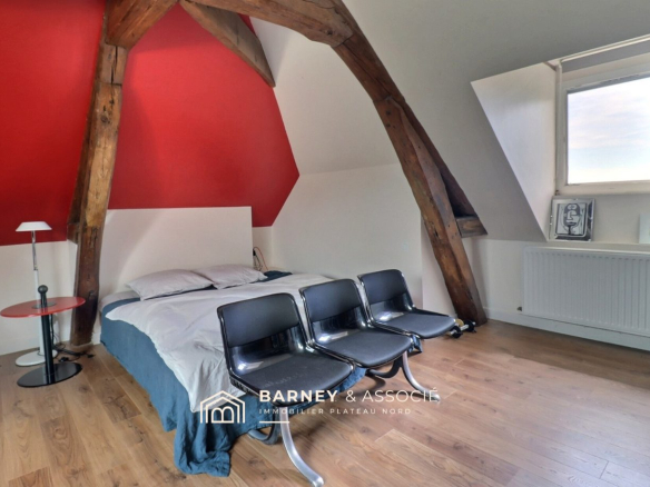 Room with exposed beams and modern furniture in an old house in Bihorel.