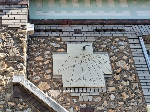 Sundial on the facade of a bourgeois house in Mont-Saint-Aignan, showcasing brick and flint architecture.