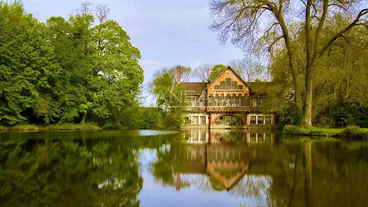 d185a8d51abd925dbbb71f06ba1dd984_35e9ed9f6d_1186-original Brick riverside house with a gabled roof, nestled among green trees and reflected in a calm lake.