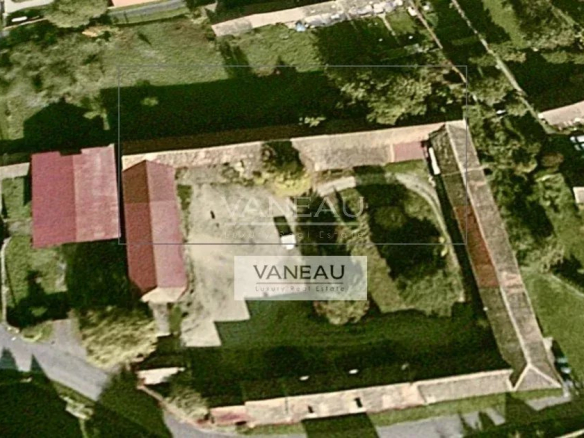 Aerial view of a historic property with red-roofed buildings inside a stone-walled enclosure and surrounding greenery.