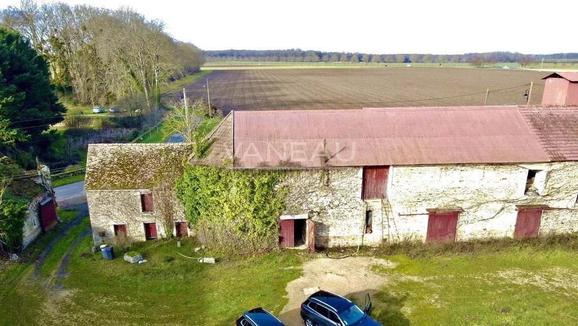 6195072698a3b2c11b52fb7176c36c17_e0c408525c_1180-original Aerial view of a weathered stone barn with red doors and ivy growing up the wall, in a rural farmland setting with fields beyond.