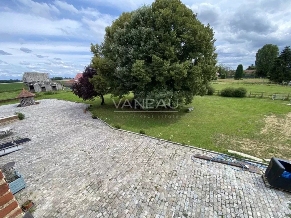 Vue extérieure du Manoir Henri IV avec un grand jardin et des arbres, à Saint-André-sur-Cailly.