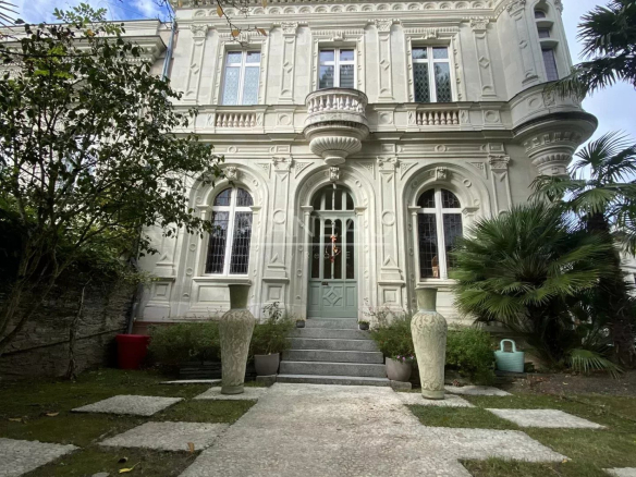 Façade d'un manoir rénové avec jardin et piscine à Angers, entouré de verdure.