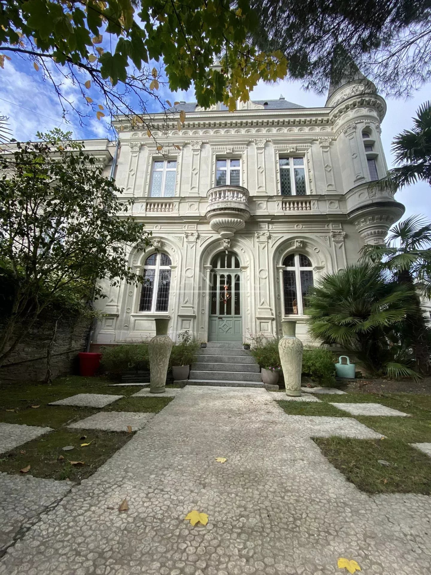 Façade d'un manoir rénové avec jardin et piscine à Angers, entouré de verdure.