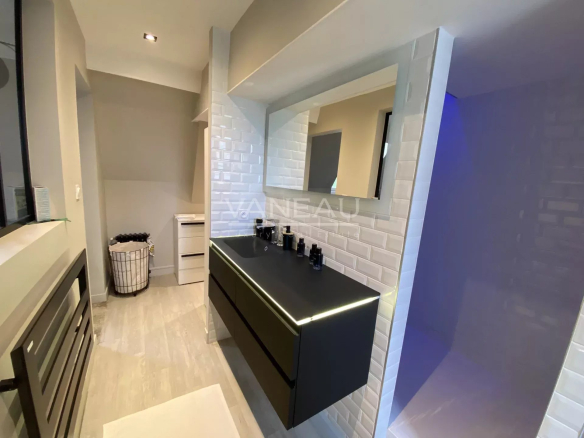 Salle de bain moderne avec meuble noir et miroir lumineux, dans un manoir rénové à Angers.