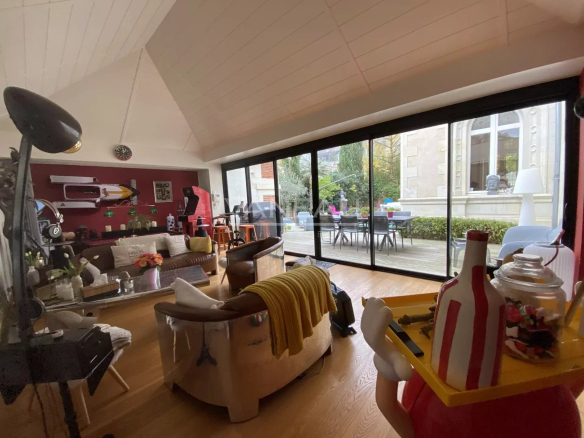Intérieur d'un manoir rénové à Angers, avec un salon lumineux et accès à une terrasse.