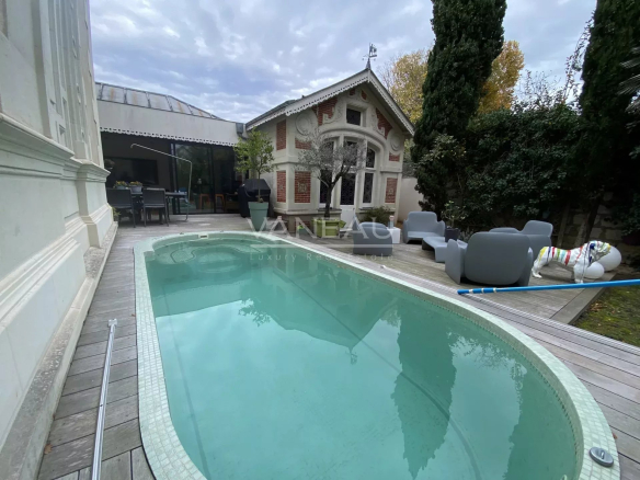 Piscine dans un manoir rénové à Angers, entourée de jardin et de mobilier extérieur.