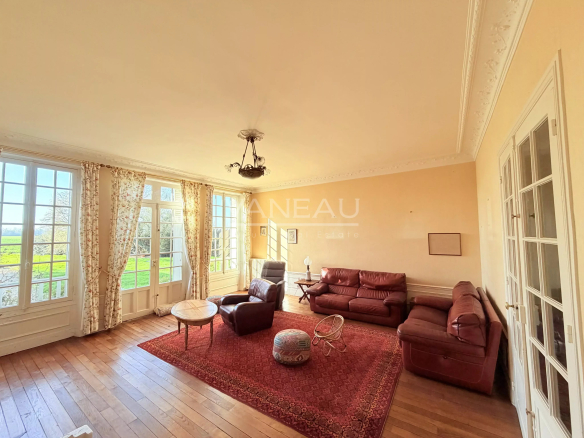 Interior of a historic farmhouse with a spacious living room and windows overlooking nature.