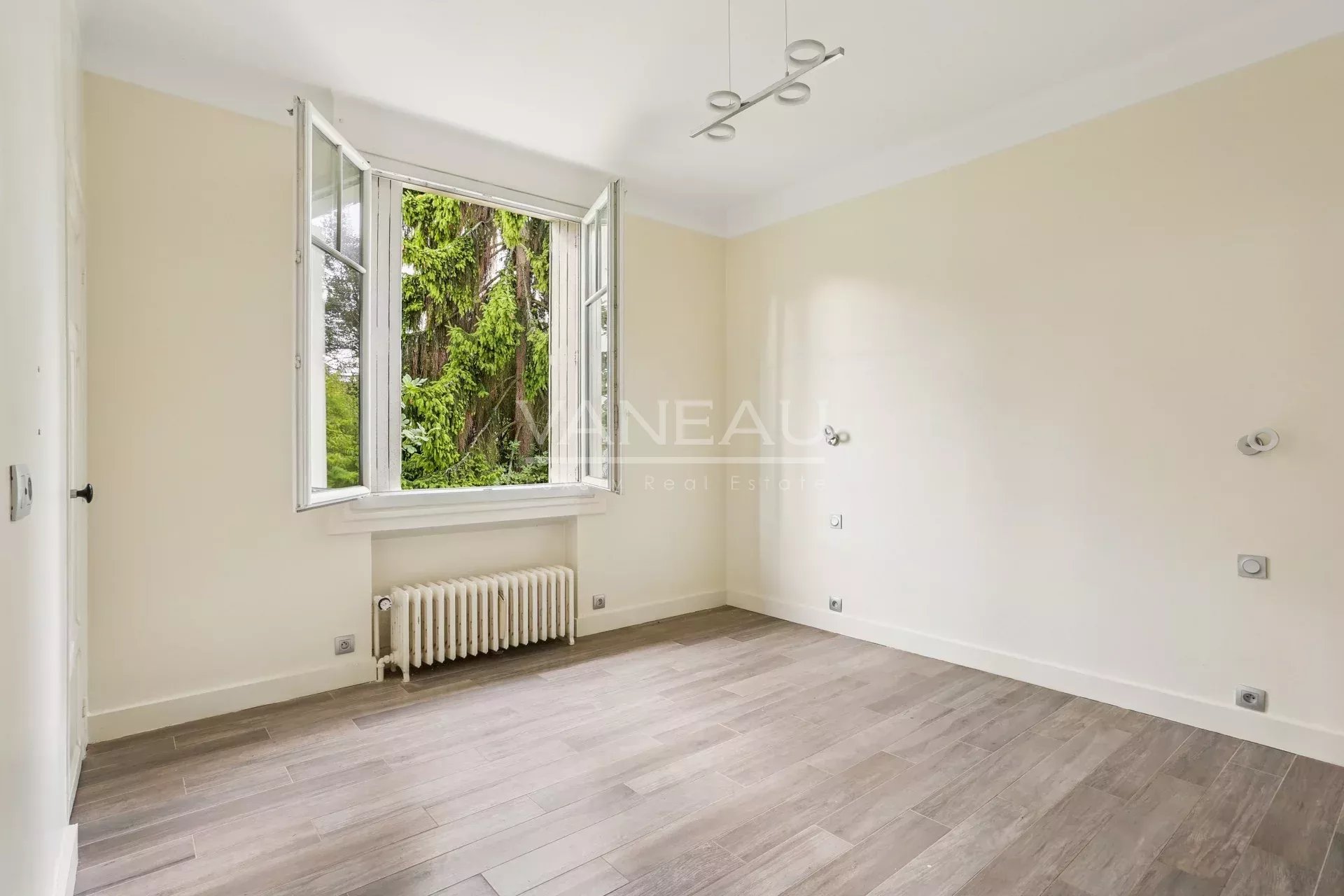 Chambre lumineuse dans une maison à Sceaux Intérieur d'une chambre lumineuse avec fenêtres ouvertes, parquet et murs clairs.
