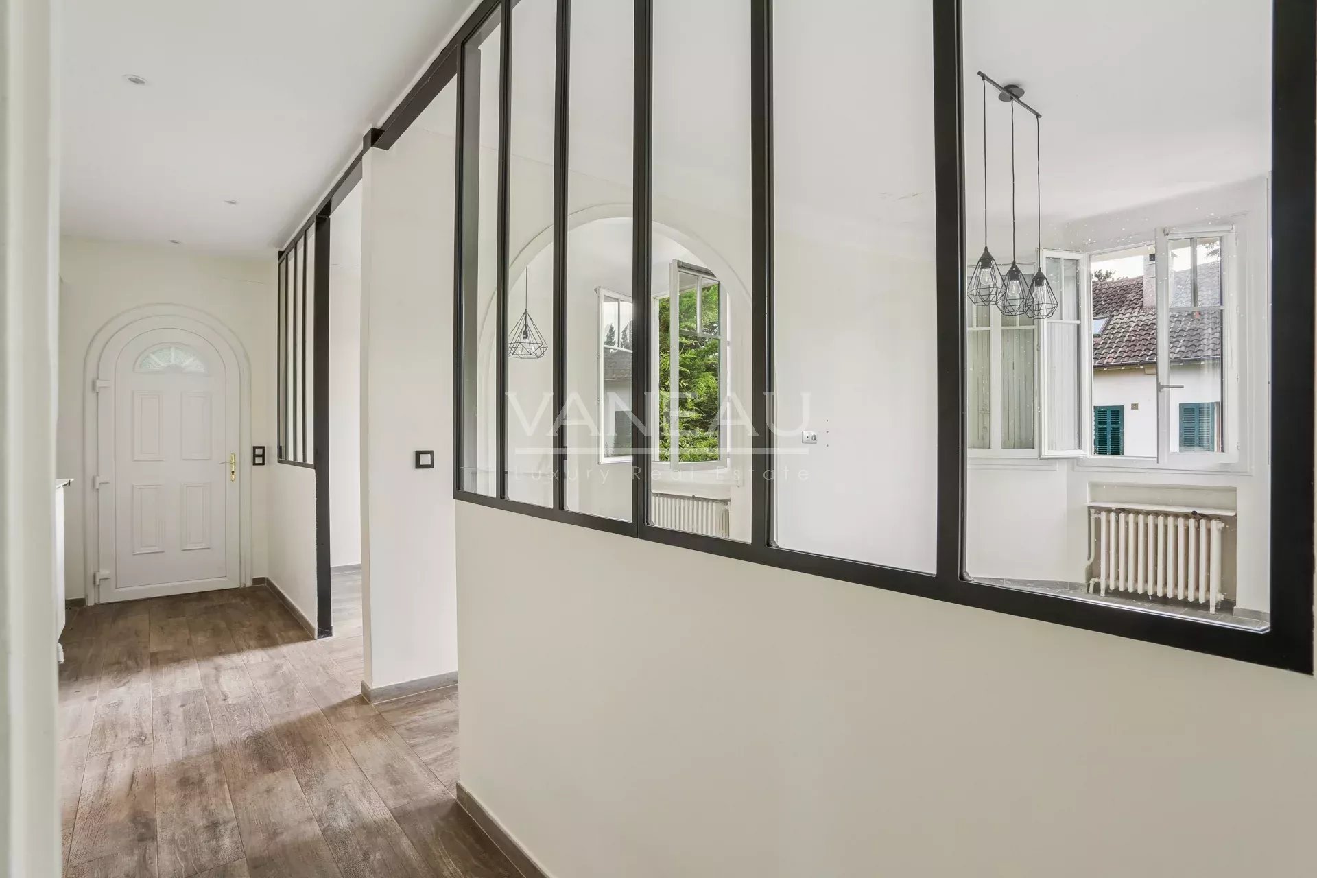 Intérieur d’une maison familiale à Sceaux Intérieur d'une maison rénovée avec un couloir lumineux et des fenêtres en verre.