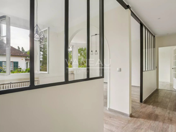 Intérieur d'une maison rénovée avec des murs en verre et un sol en bois.